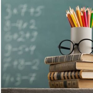 Stack of books, glasses and coloured pencils in front of a chalkboard with sums