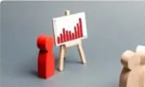 Wooden figures in front of a small presentation board with a chart